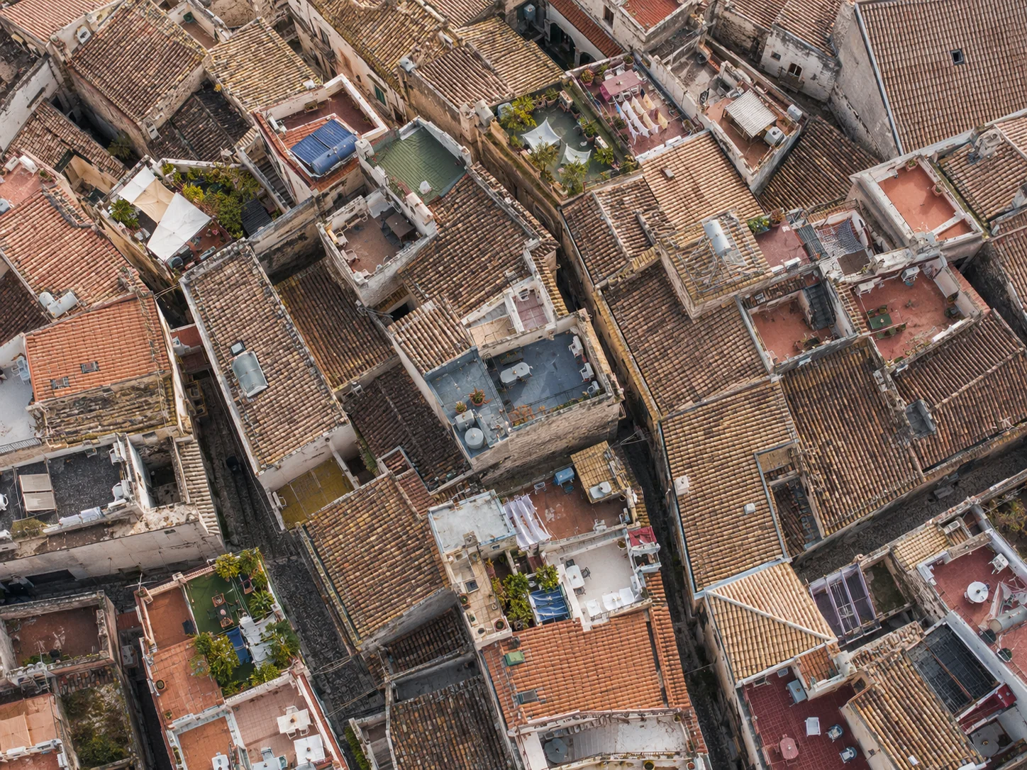 Mediterranean rooftop maze from above with terraces, alleys and terracotta tiles