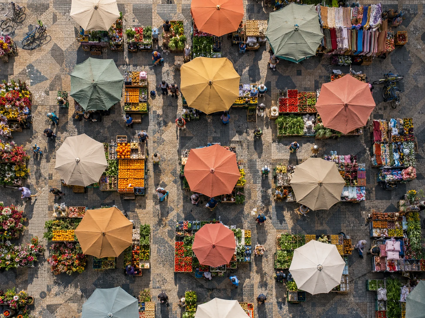 Market square from directly above with umbrellas, produce crates, flowers and walkways